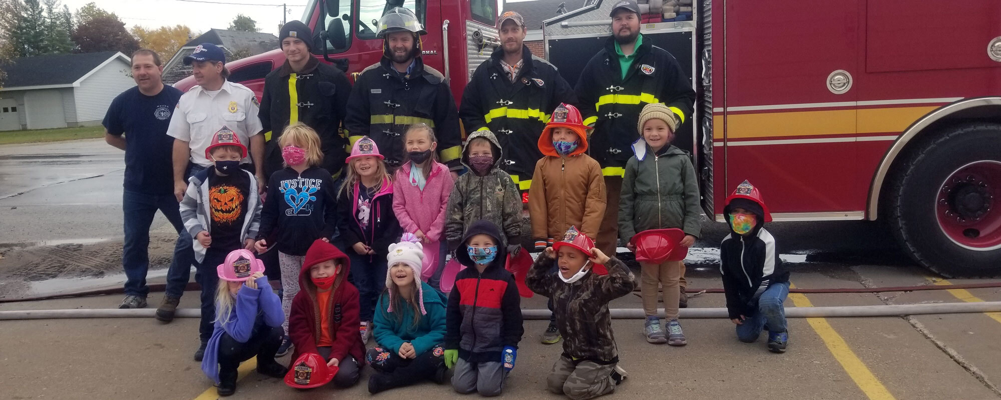 Kindergarten students pose with the fire department in front of a fire truck